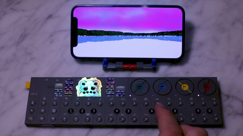 Phone screen showing a pink sky over Sognsvann lake above an OP-Z synth